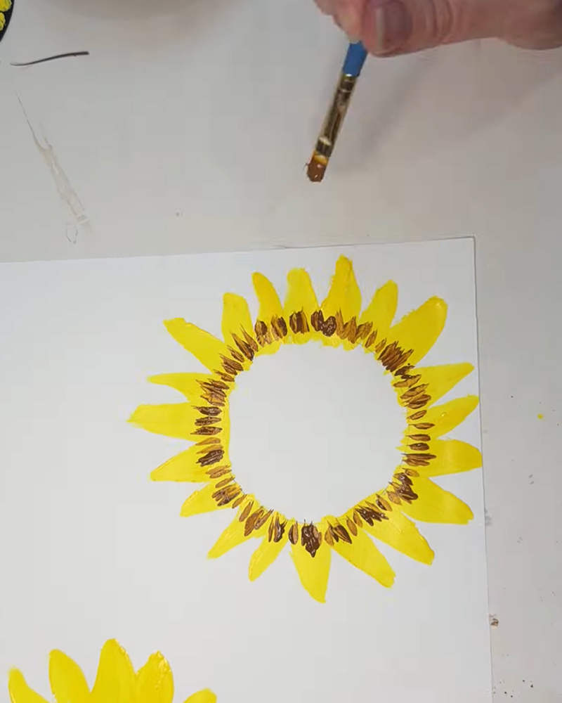 Adding brown details around the sunflower center.