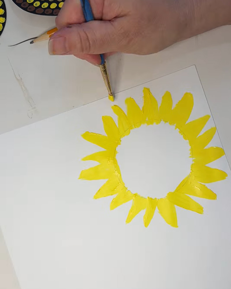 Painting yellow sunflower petals with a brush.